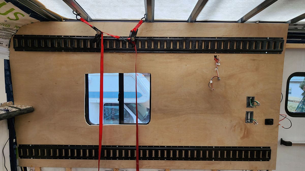 Ratchet strap holding the top plywood in place for screwing into the furring strips.